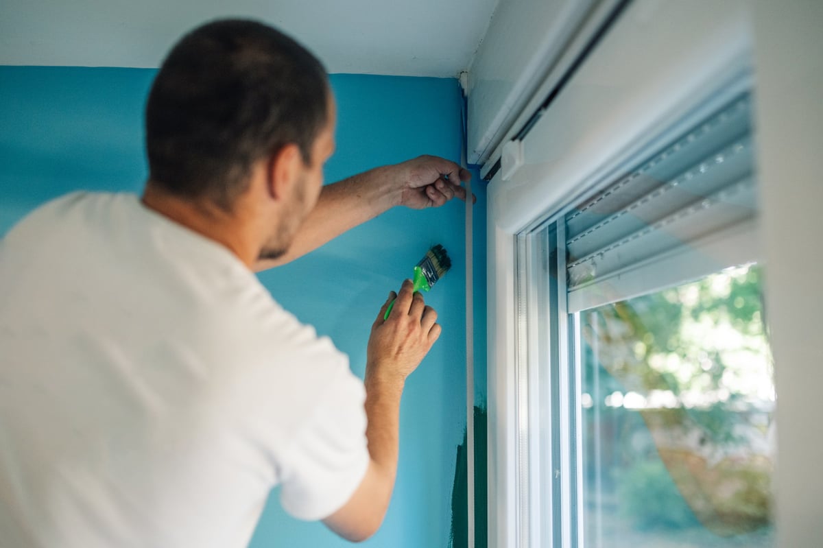 Professional painter applying masking tape around a window frame